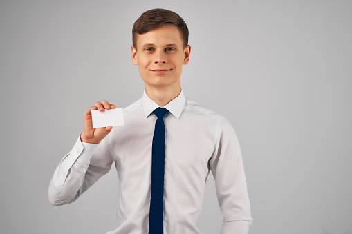 a man in a shirt with a tie holding a business card advertising Copy Space. High quality photo