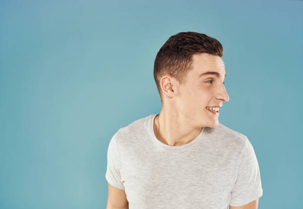 istock Cute man holds his hand behind his head emotions blue background white t-shirt 2057330577