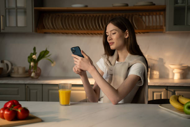 istock Young Woman Using Smartphone in Modern Kitchen During Breakfast Time 2057341837
