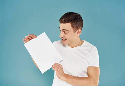 Male advertiser with a white sheet of paper on a blue background mockup Flyer. High quality photo