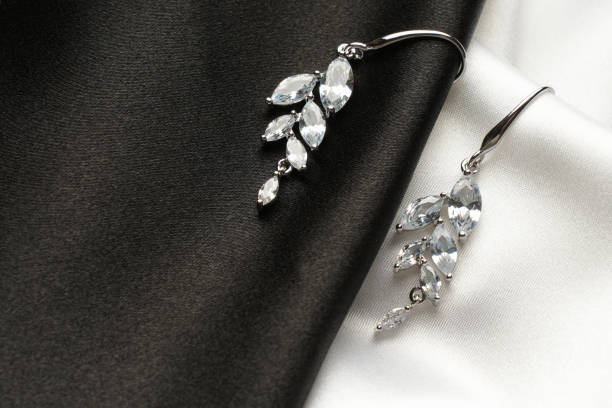 istock Jewelry. Silver earrings with diamonds on black silk background 2057354431