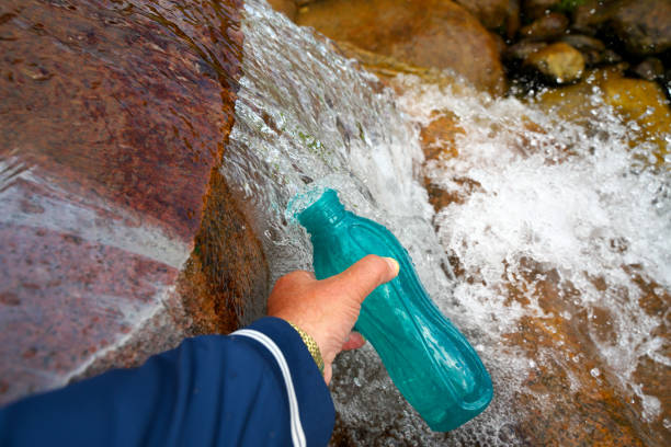 The source of water is collected in a bottle. Pure mineral spring water. Selective focus.