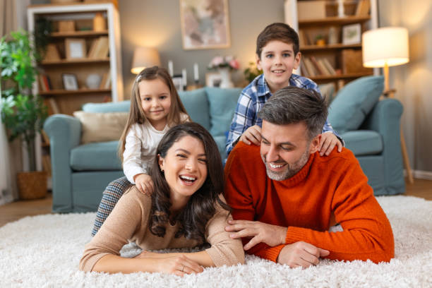 istock Happy parents and their small kids talking while lying on carpet at home. 2057368730