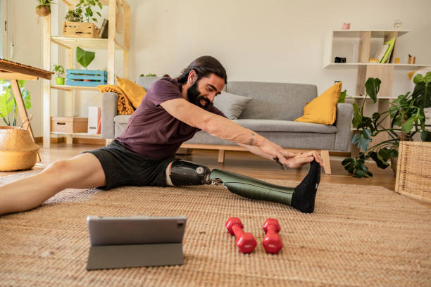 istock man amputated leg prosthesis, sport at home online class doing stretching and weight training 2057414364
