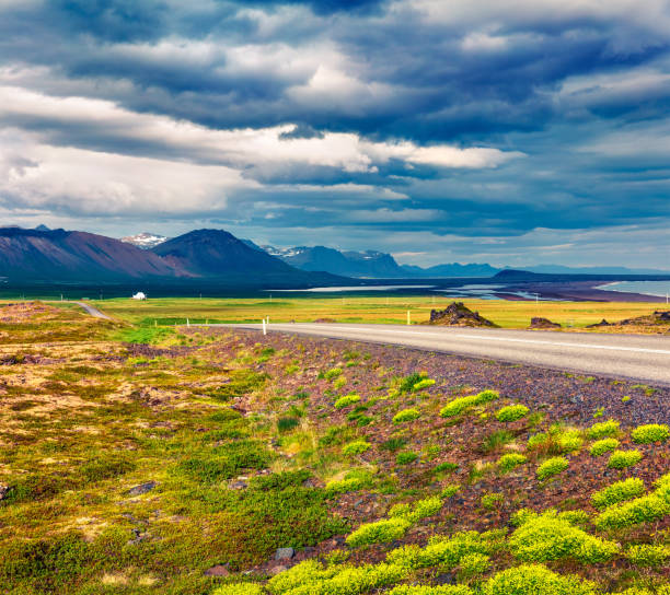Empty asphalt road with colorful cloudy sky. Beautiful outdoor scenery in Iceland, Europe. Beautiful outdoor scenery in Iceland, Europe. Image of travel concept background.