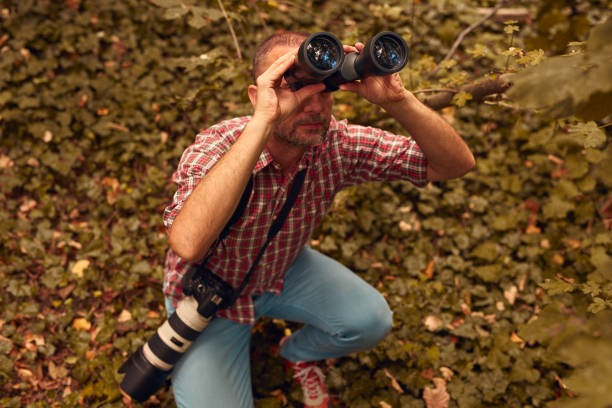 istock Man using binoculars and camera for bird and animal watching in nature. 2057497054
