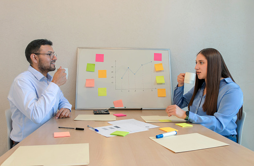 man and woman sitting at a table with a white board and sticky notes