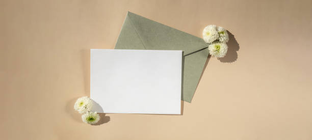istock Beautiful little white flowers on postal green envelope on beige background, empty paper note copy space for text, spring time, greeting card for holiday. Flower delivery 2057540944