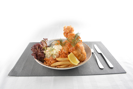 chef deep fried golden fish and chips with tartar sauce, lemon , French fries and salad dressing in plate on white table restaurant luxury hotel western cafe halal menu