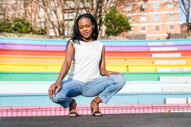 Confident Afro-American Female Crouching Against Rainbow Wall