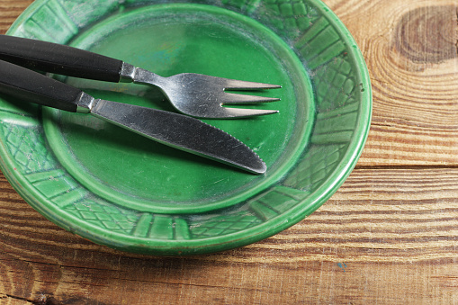 Green plate and cutlery on old wooden background close-up
