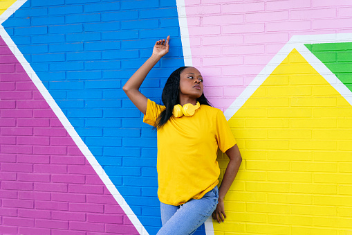 Confident woman leaning on a multicolored wall, looking away