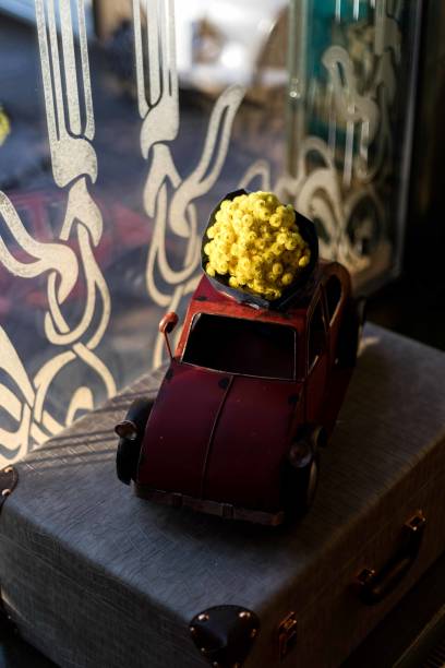Old car toy lit with window light, sitting on an old suitcase in a restaurant.