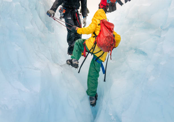 istock Unrecognizable tour guide helping woman climbing up glacier crevasse using ropes. Exit Glacier ice hiking. Alaska. 2057576109