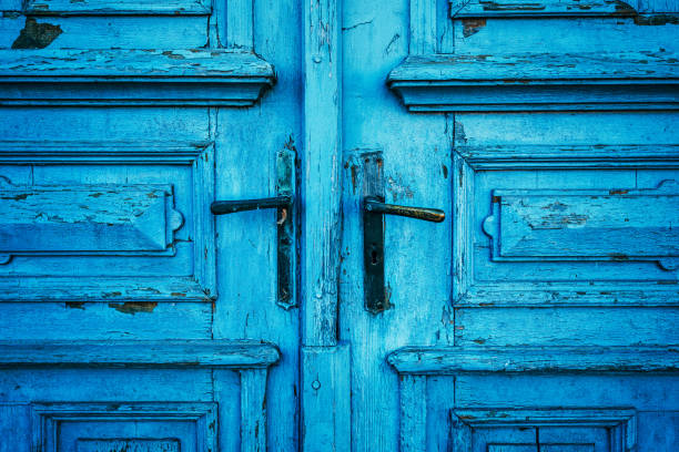 Old blue massive wooden door with two handles as background