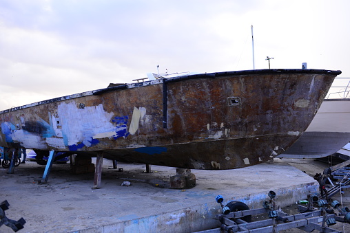 a large, neglected boat standing on the shore