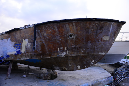 a large, neglected boat standing on the shore