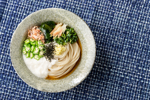 Bukkake udon is boiled udon noodles topped with grated yam, ginger, green onion, wakame, and dried bonito flakes.