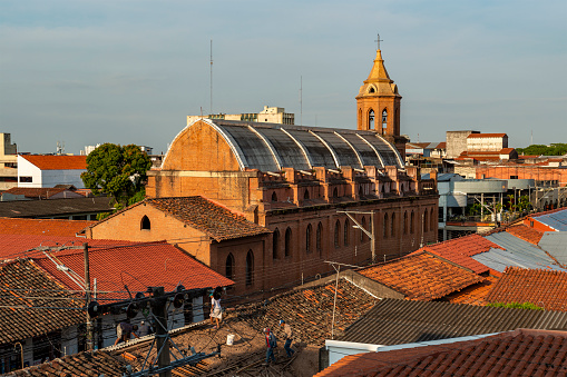 Merced church at sunrise with people working on the roof of a house, Santa Cruz de la Sierra, Bolivia.