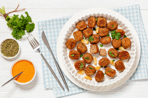 lihapullat, baked in oven chicken meatballs in white baking dish on white wooden table with chili mayonnaise and cutlery, finnish cuisine, horizontal view from above, flat lay