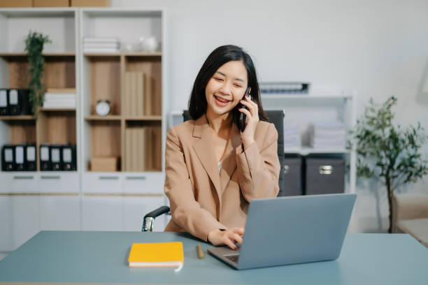 istock Young beautiful woman typing on tablet and laptop while sitting at the working white table 2057643900