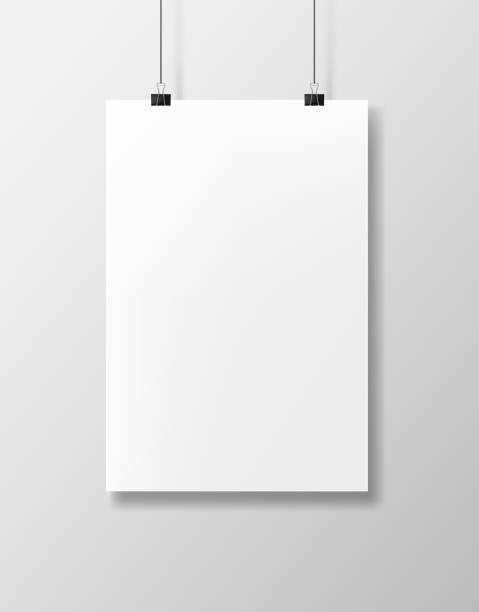A blank white paper of poster A blank white paper of poster with binders clip hangs against a gray wall. Empty template. poster stock illustrations