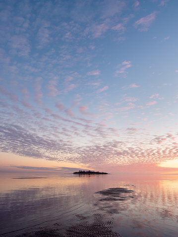 Amazingly beautiful pastel colored sunset by the calm sea with fluffy clouds in the sky reflected on the water surface, Bothnian Bay, Baltic Sea, Finland