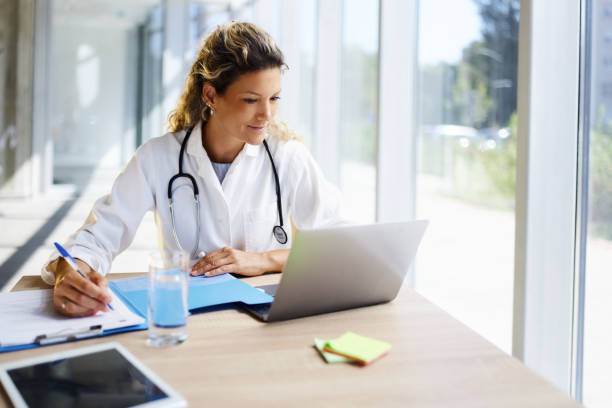 istock Female doctor taking notes while working on laptop in the office. 2057722497