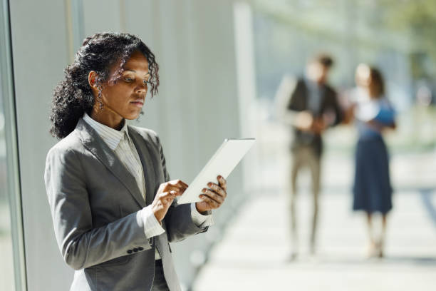 Young black businesswoman working on touchpad in a hallway.