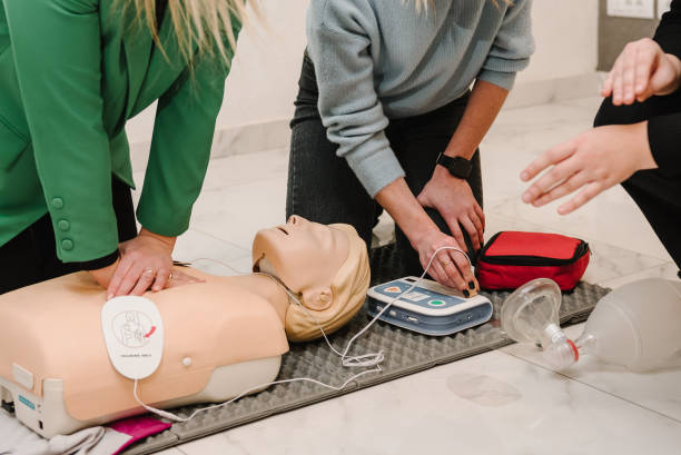 automated external defibrillator device, aed with training dummy mannequin. use an automatic defibrillator in conducting basic cardiopulmonary resuscitation of victim. demonstrating chest compressions - treinar imagens e fotografias de stock