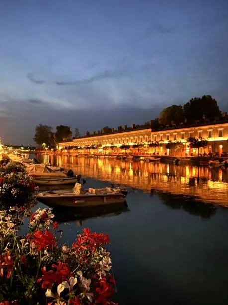 Peschiera del Garda is one of the most beautiful small towns of the lake, with Unesco Heritage sites, canals, bridges and Roman ruins. Selective focus on foreground flowers.