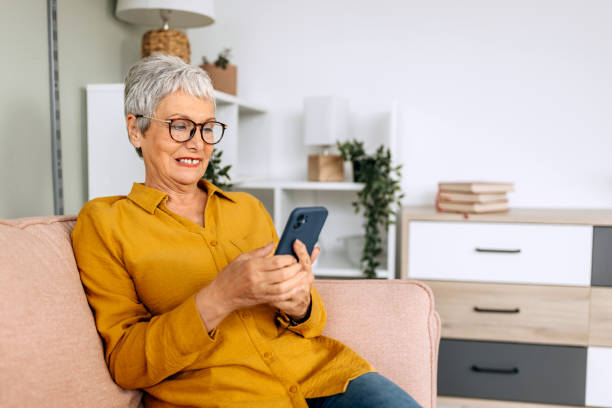 istock Shot of a senior woman using a mobile phone at home while sitting on a sofa 2057759569