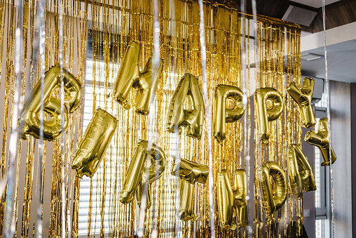 Birthday party. Happy birthday, text. Arch decorated with golden balloons. Photo-wall decoration with gold background. Trendy autumn decor. Celebration concept.