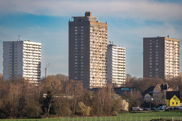 telephoto shot of three residential silos with windows, balconies, antennas in the afternoon sunlight with unleafy trees in the foreground and light cloud cover - plattenbau homes architectural detail architecture and buildings imagens e fotografias de stock