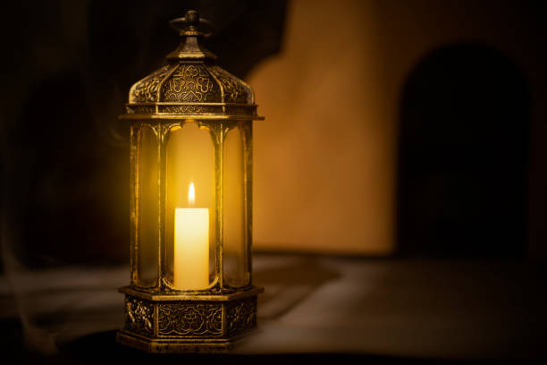 Ornamental Arabic lantern with burning candle glowing with a dark background. Ramadan concept