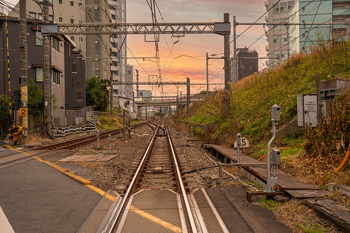 A picture of an urban level railway crossing during sunset