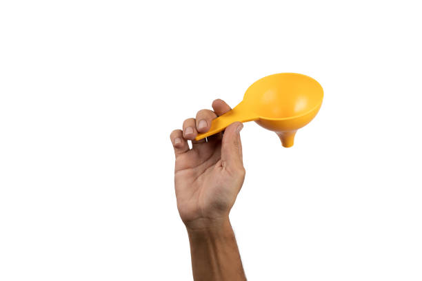 istock Black male hand holding a yellow kitchen funnel isolated, no background. 2057781034