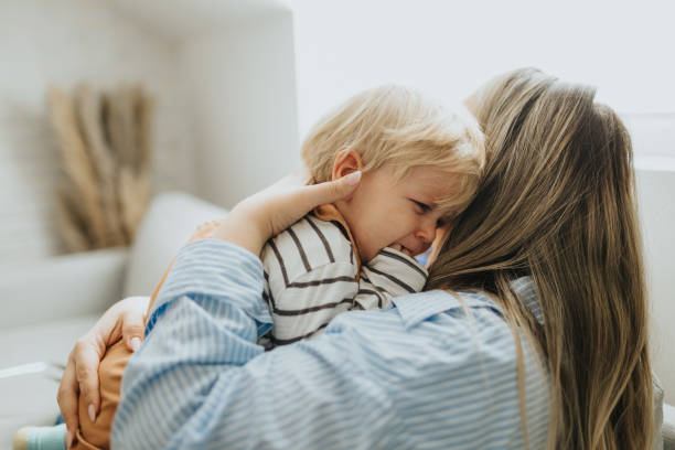 istock Devoted mother hugging and comforting her son on sofa 2057805172