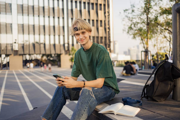 istock Smiling male student using smart phone on city street. 2057813634