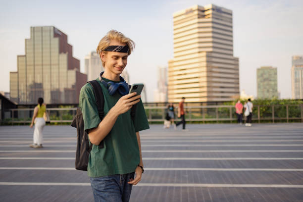 Smiling man using cell phone during a walk in the city.