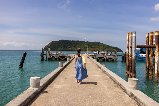 Thai woman walking on a pier by the sea outdoors.