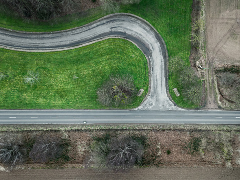 Drone top down view of an abstract road in the rural English countryside. A single cyclist can be seen on the straight road.