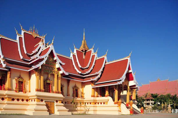 Vientiane, Laos: Ho Thammasapha - Dharma Hall - Laos' Buddhist headquarters and residence of the Supreme Patriach (Pha Sangkharat) of Lao Buddhism - Theravada Buddhism is by far the most prominent organized religion in the country, with more than 4,000 temples - ornate building with multi-tiered roofs on That Luang park, next to Wat That Luang Neua (far right) Saysettha Park, Ban Thatluang.