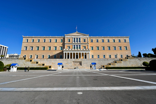 Athens, Greece - December18, 2023: The parliament building on Syntagma Square with the guards called Evzone in traditional uniform, relief as war memorail to the unknown soldier