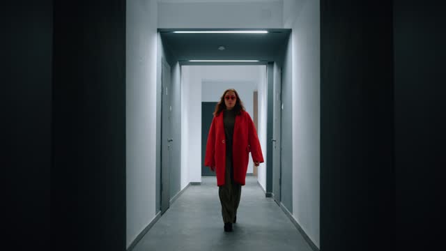 Woman in red enters the corridor and walks quickly along it