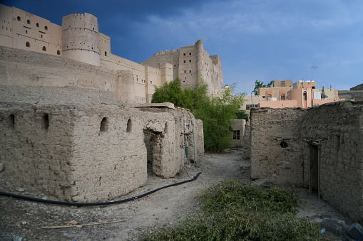 Ruins of village with historic Bahla Fort in background, Oman.