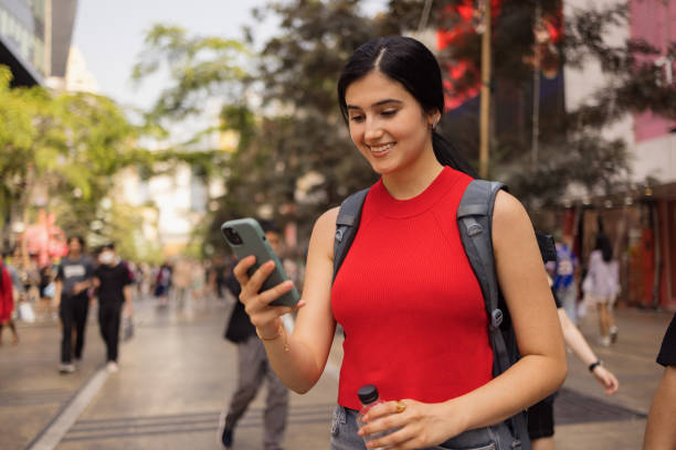 istock Happy female student using cell phone on the city street. 2057917593