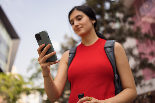 Carefree female tourist reading a text message on smart phone at the street. Focus is on hand and phone.