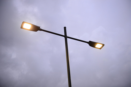 Tall street lights hanging on the metal pole front of the blue sky