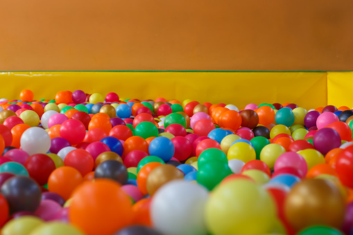 Little boy playing in dry pool with plastic balls in the nursery. Close-up leisure activities indoors. Positive emotions background. School holidays. Copy space